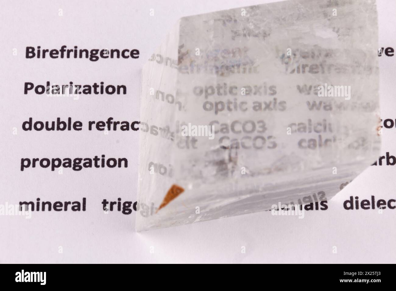 Biréfringence optique démontrée à l'aide d'un texte à l'aide d'un cristal de calcite double espar naturel, d'un plan macro et d'ombres réelles Banque D'Images