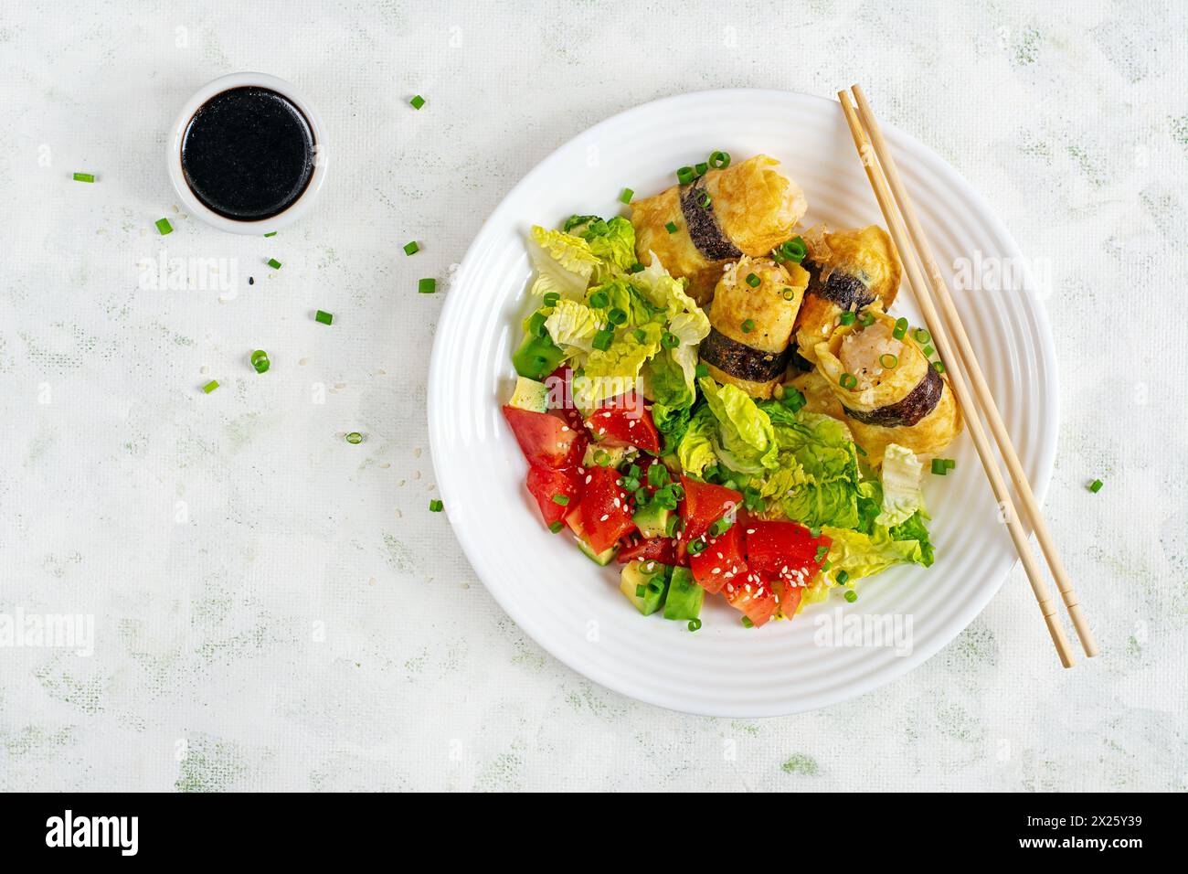Rouleaux d'œufs coréens. Oeufs roulés d'omelette avec riz, nori et salade fraîche sur une assiette blanche. Délicieux hors-d'œuvre farci à l'omelette. Vue de dessus Banque D'Images