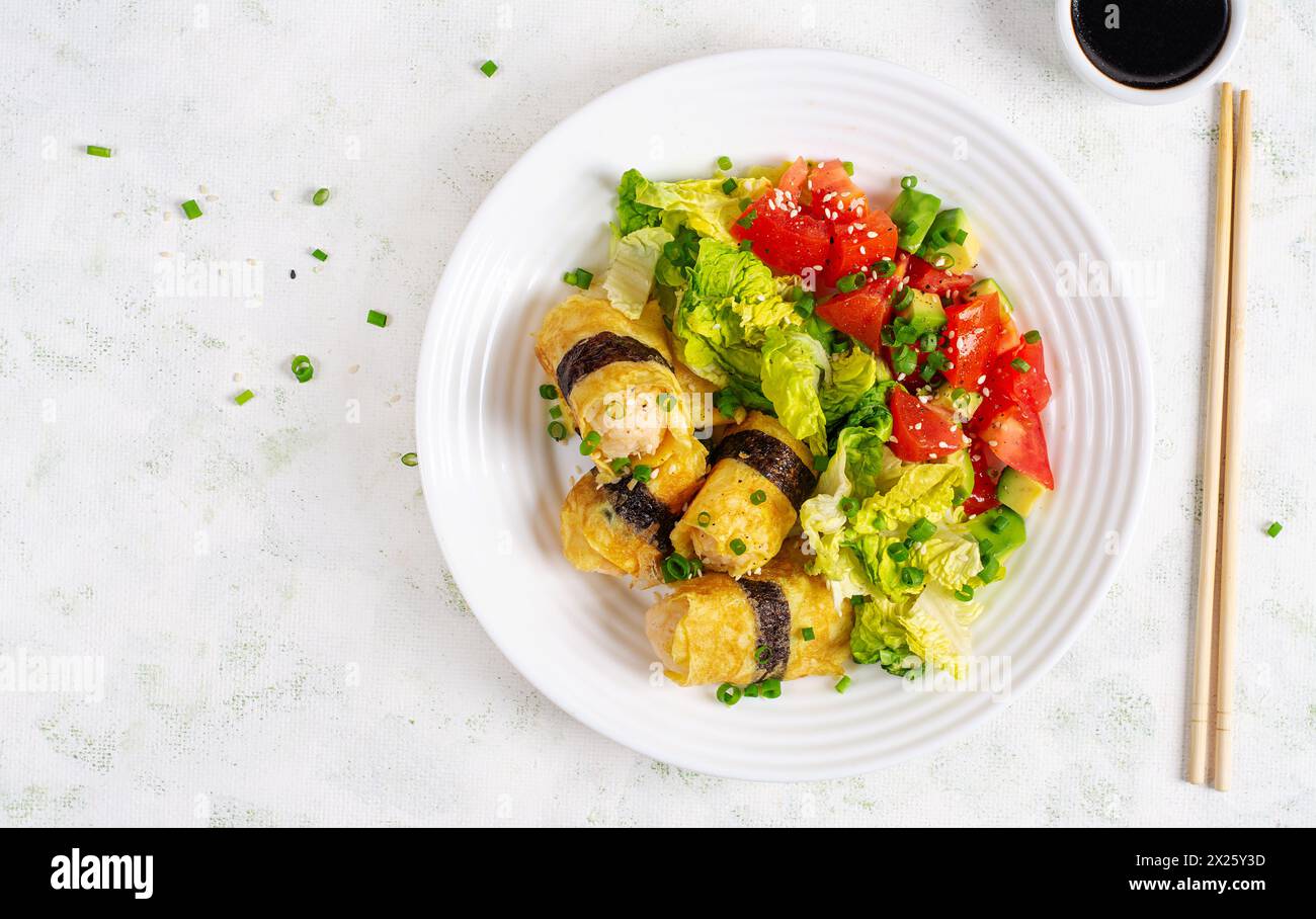 Rouleaux d'œufs coréens. Oeufs roulés d'omelette avec riz, nori et salade fraîche sur une assiette blanche. Délicieux hors-d'œuvre farci à l'omelette. Vue de dessus Banque D'Images