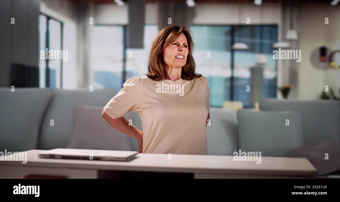 Jeune femme assise sur le canapé ayant mal au dos Banque D'Images