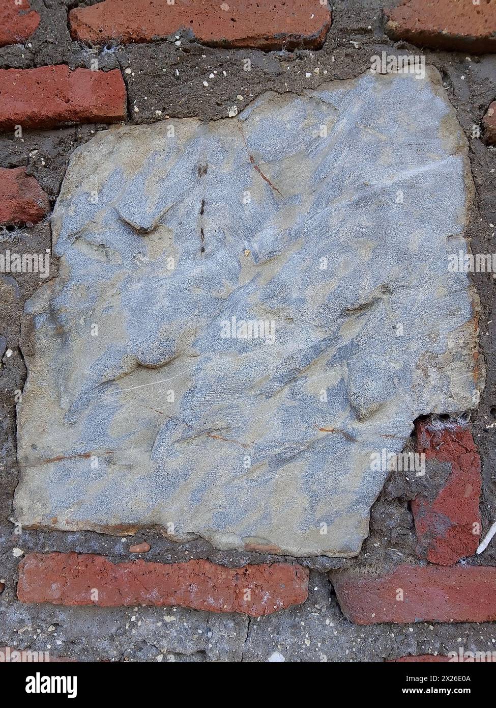 Ce paysage urbain fascinant révèle une formation rocheuse organique enfermée dans un cadre de briques rouges vieillies et de gravats. Les tons gris-bleu marbré an Banque D'Images