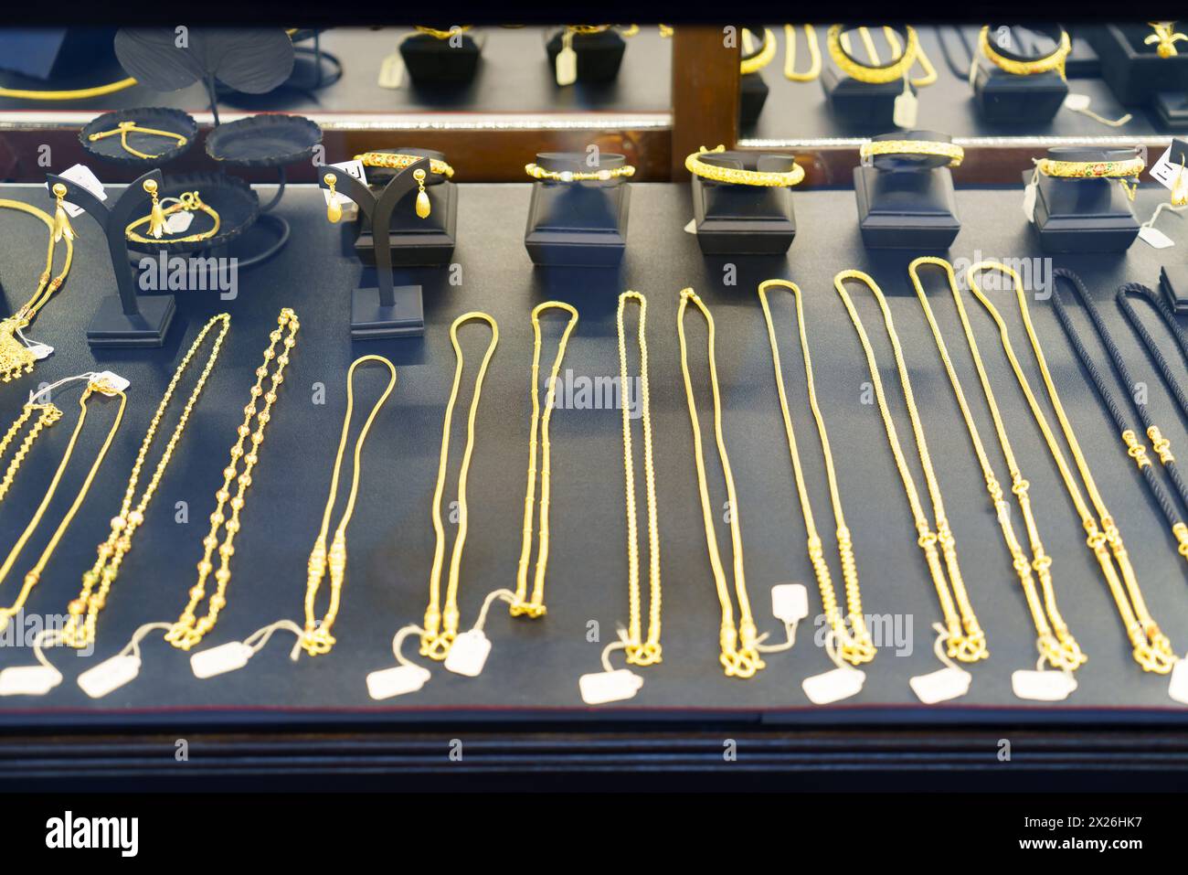 Découvrez l'attrait de l'opulence de près avec une vue détaillée des colliers, bagues et chaînes en or élégamment présentés dans un magasin de beauté Wind Banque D'Images