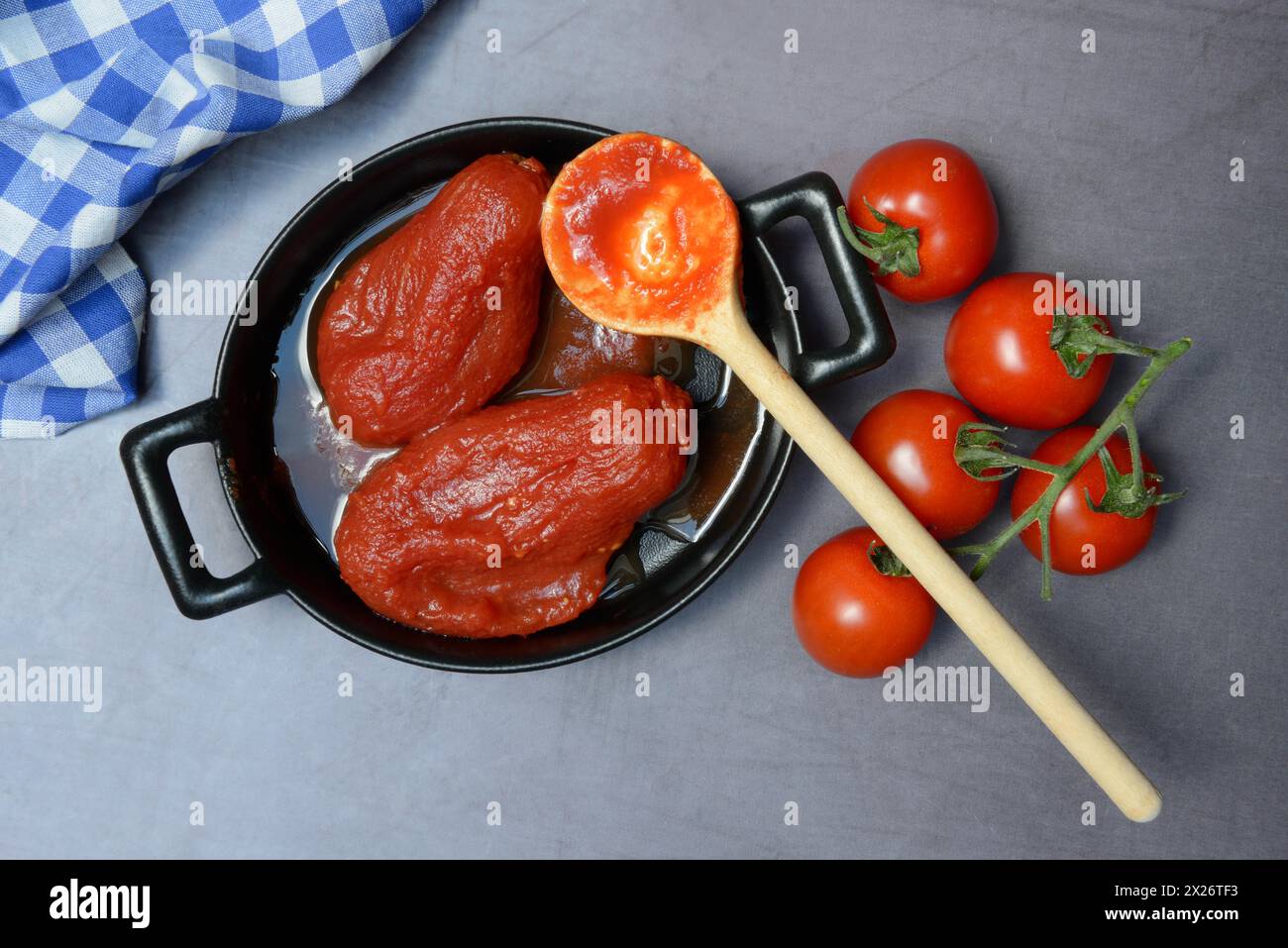 Tomates entières en boîte dans un pot, tomates et cuillère en bois Banque D'Images