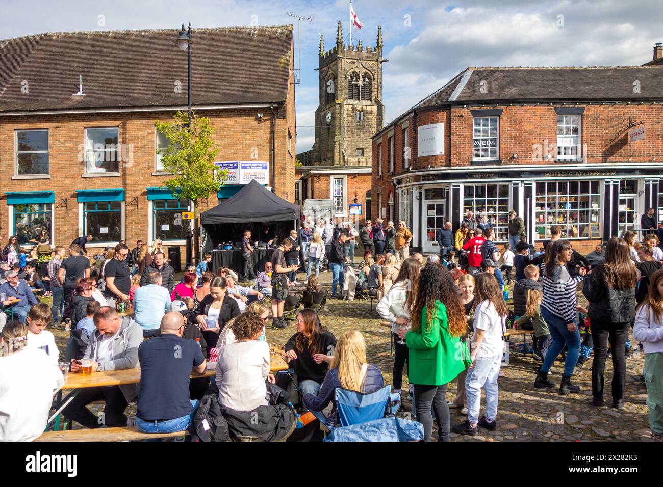 Fêtards et festivaliers appréciant le soleil de printemps sur la place du marché pavée de la ville de Sandbach dans le Cheshire au festival de musique Banque D'Images