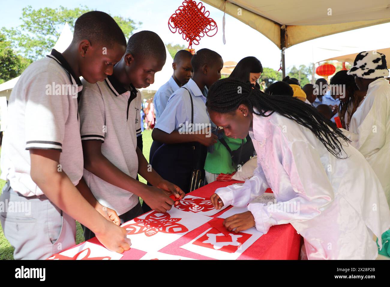 Kampala, Ouganda. 20 avril 2024. Les étudiants apprennent l'art traditionnel chinois de la découpe du papier lors de la 15e célébration de la Journée de la langue chinoise de l'ONU à l'Université Makerere, Kampala, Ouganda, le 20 avril 2024. Les représentants des apprenants d'environ 50 écoles secondaires et établissements d'enseignement supérieur se sont réunis samedi à l'Université Makerere en Ouganda pour célébrer la Journée des Nations Unies de la langue chinoise. Crédit : Hajarah Nalwadda/Xinhua/Alamy Live News Banque D'Images