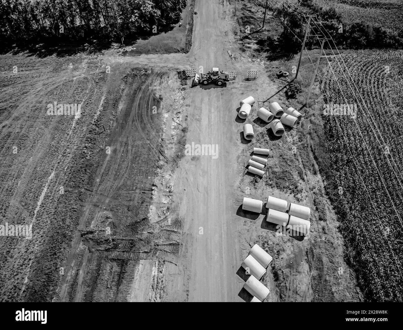 Vue à angle élevé d'un projet de construction de route coupant à travers un quartier agricole de champs agricoles. Banque D'Images