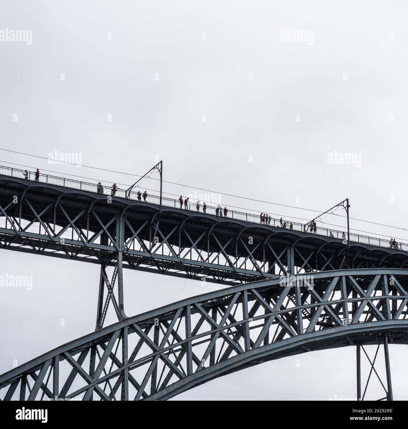 Touristes marchant, prenant des photos et une femme posant depuis la plate-forme supérieure du pont en acier Don Luis I où le métro de Porto passe avec le nuage de pluie Banque D'Images