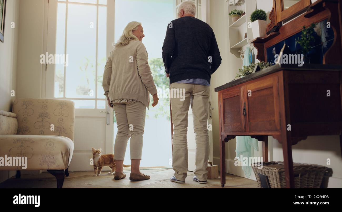 Sourire, couple senior et porte à la maison ensemble pour la conversation, retour et partir pour la promenade avec chat de compagnie. Retraite, homme âgé et femme heureuse Banque D'Images