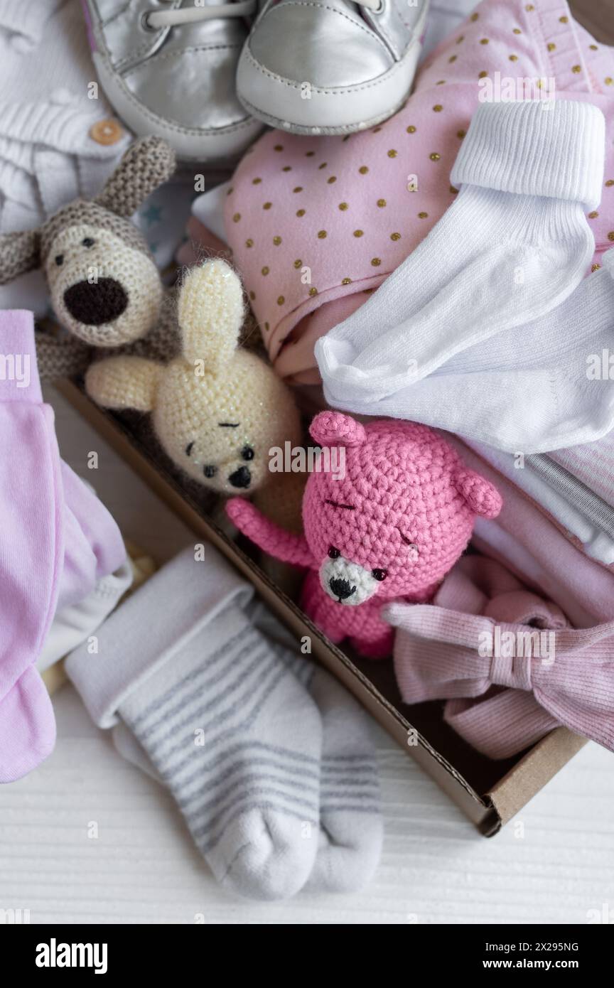 Vêtements de bébé, jouets tricotés, chaussettes et chaussures en boîte. Idée de vêtements d'occasion, don, concept de charité Banque D'Images