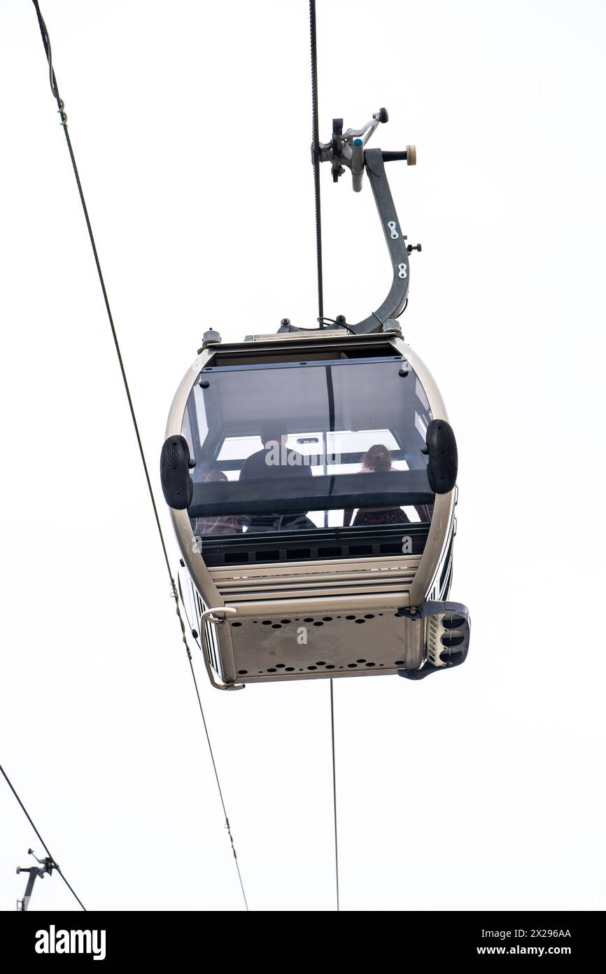 Une famille bénéficiant de vues aériennes à l'intérieur d'une télécabine de Vilanova de Gaia suspendue aux câbles d'acier suspendus sous un ciel blanc nuageux à Porto. Banque D'Images