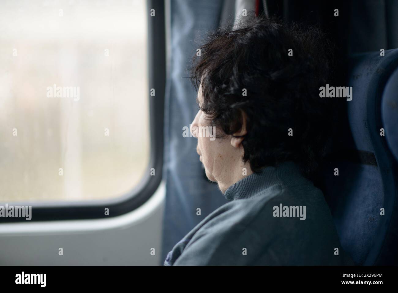 Une femme âgée en contemplation par la fenêtre d'un train, paysage passant par Banque D'Images