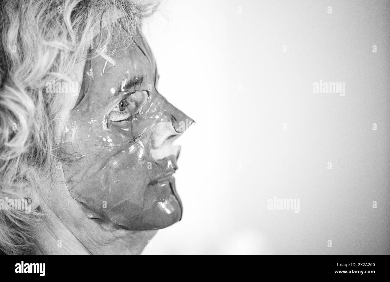 Femme d'âge moyen mature utilisant un masque facial en gel violet pour la peau et les soins de beauté Banque D'Images