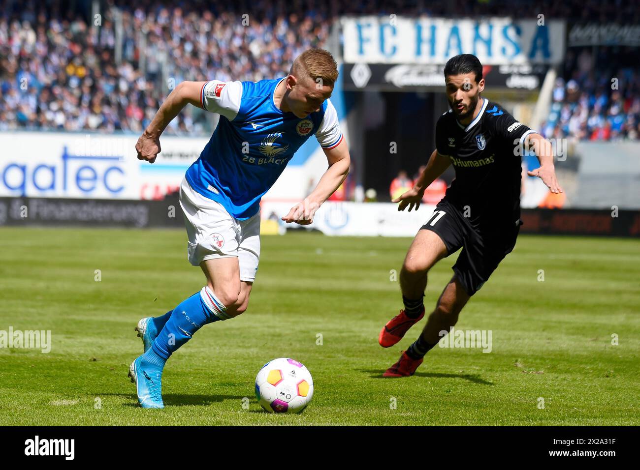 Rostock, Allemagne. 21 avril 2024. Football : Bundesliga 2, Hansa Rostock - 1. FC Magdeburg, Journée 30, Ostseestadion. Kai Pröger de Rostock tente de dépasser Mo El Hankouri de Magdebourg avec le ballon. Crédit : Gregor Fischer/dpa - REMARQUE IMPORTANTE : conformément aux règlements de la DFL German Football League et de la DFB German Football Association, il est interdit d'utiliser ou de faire utiliser des photographies prises dans le stade et/ou du match sous forme d'images séquentielles et/ou de séries de photos de type vidéo./dpa/Alamy Live News Banque D'Images