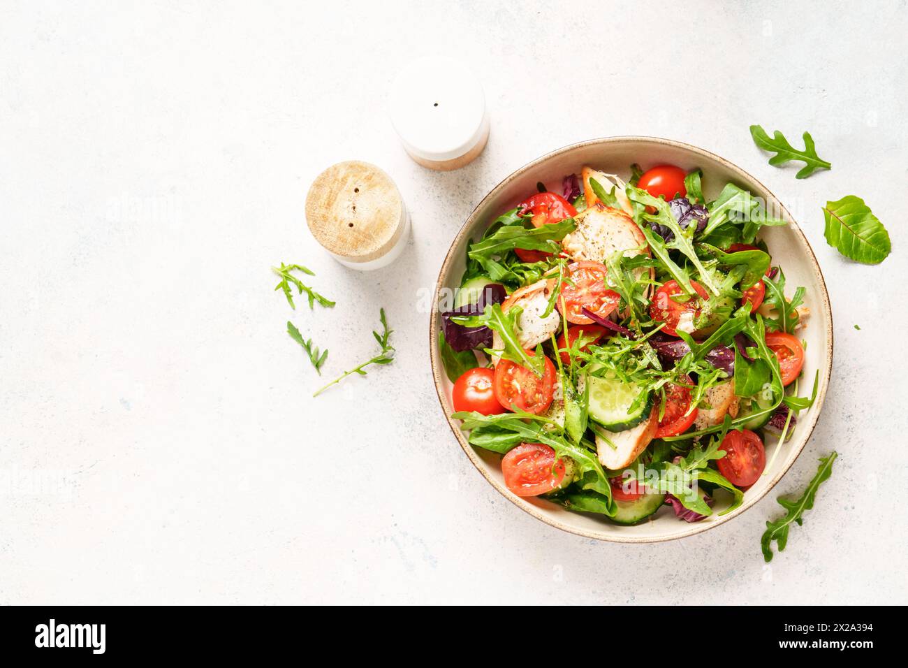 Salade verte avec poitrine de poulet cuite au four, feuilles de salade fraîches et légumes. Vue de dessus sur fond blanc. Banque D'Images