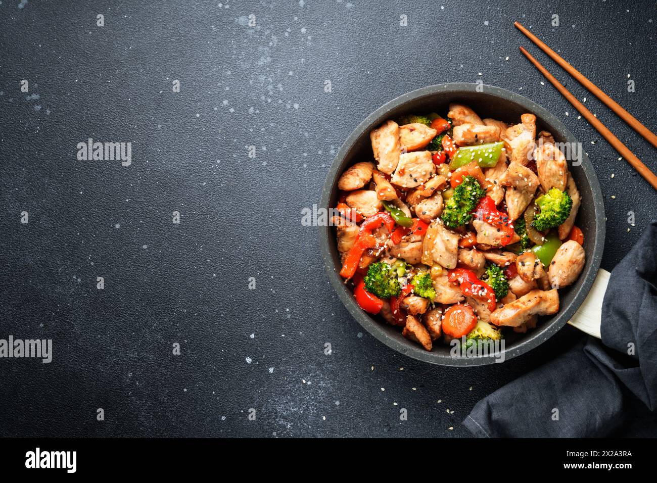 Sauté de poulet avec des légumes et du sésame sur fond noir. Cuisine asiatique traditionnelle. Banque D'Images