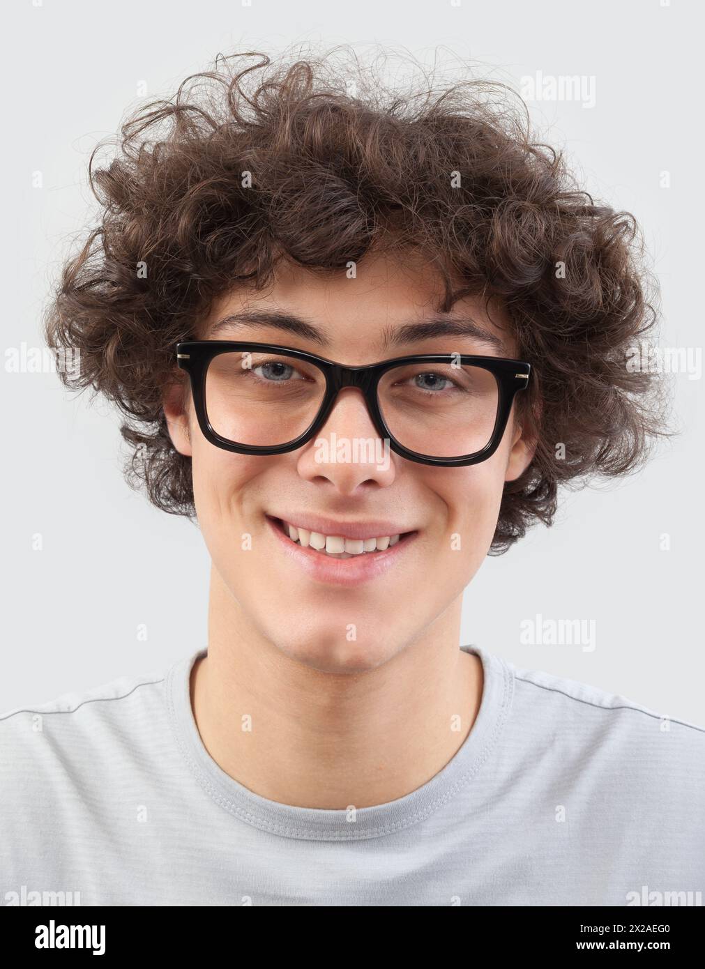 Souriant et beau, le jeune homme porte des lunettes. Il regarde dans la caméra avec ses yeux bleus, portrait d'homme avec des lunettes isolé contre un b gris Banque D'Images