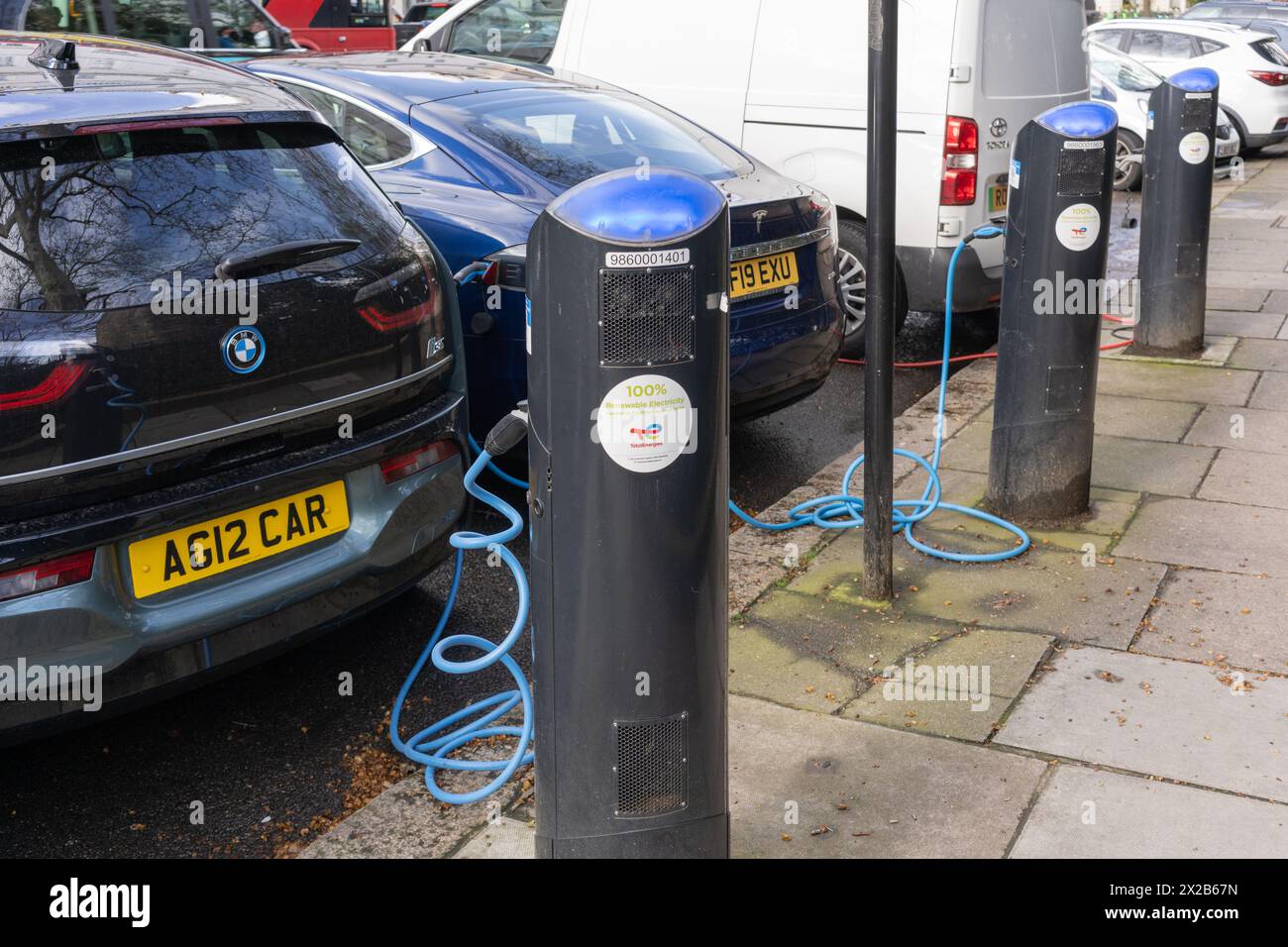 Voitures électriques - une BMW i3 et une Tesla branchées et en charge - à une borne de recharge de réseau public EV fournie par source London. Londres, Angleterre Banque D'Images