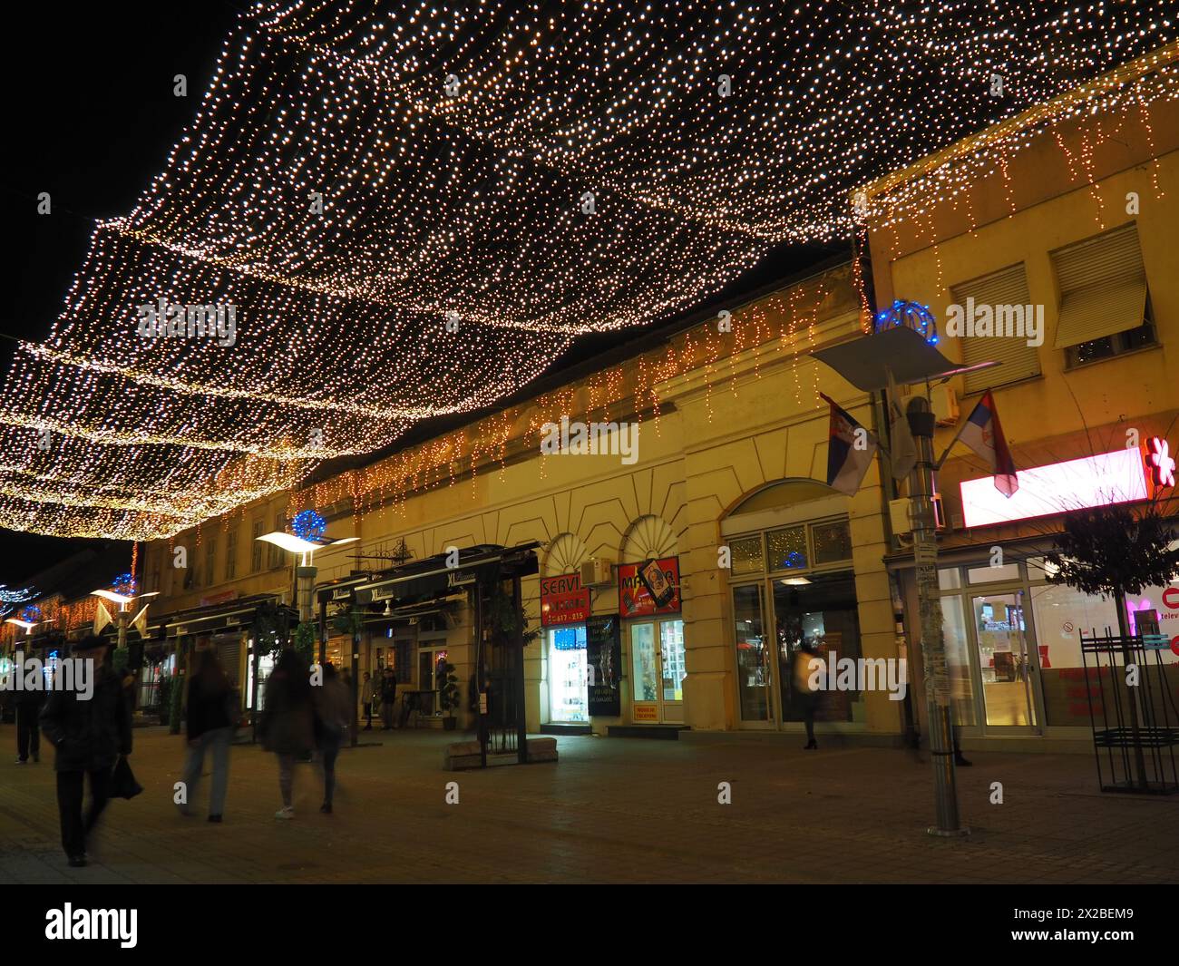 Sremska Mitrovica, Serbie, 24 décembre 2021 guirlandes suspendues. Décoration festive des rues de la ville. Guirlandes de lumières et d'ampoules jaunes, blanches et dorées Banque D'Images