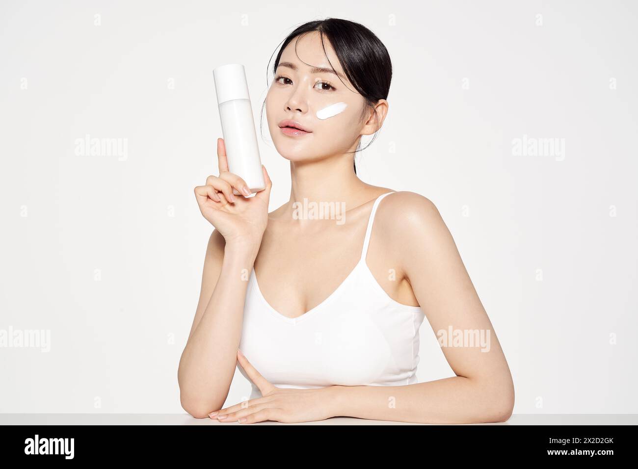 Femme asiatique pose avec White Cosmetics Bottle Banque D'Images