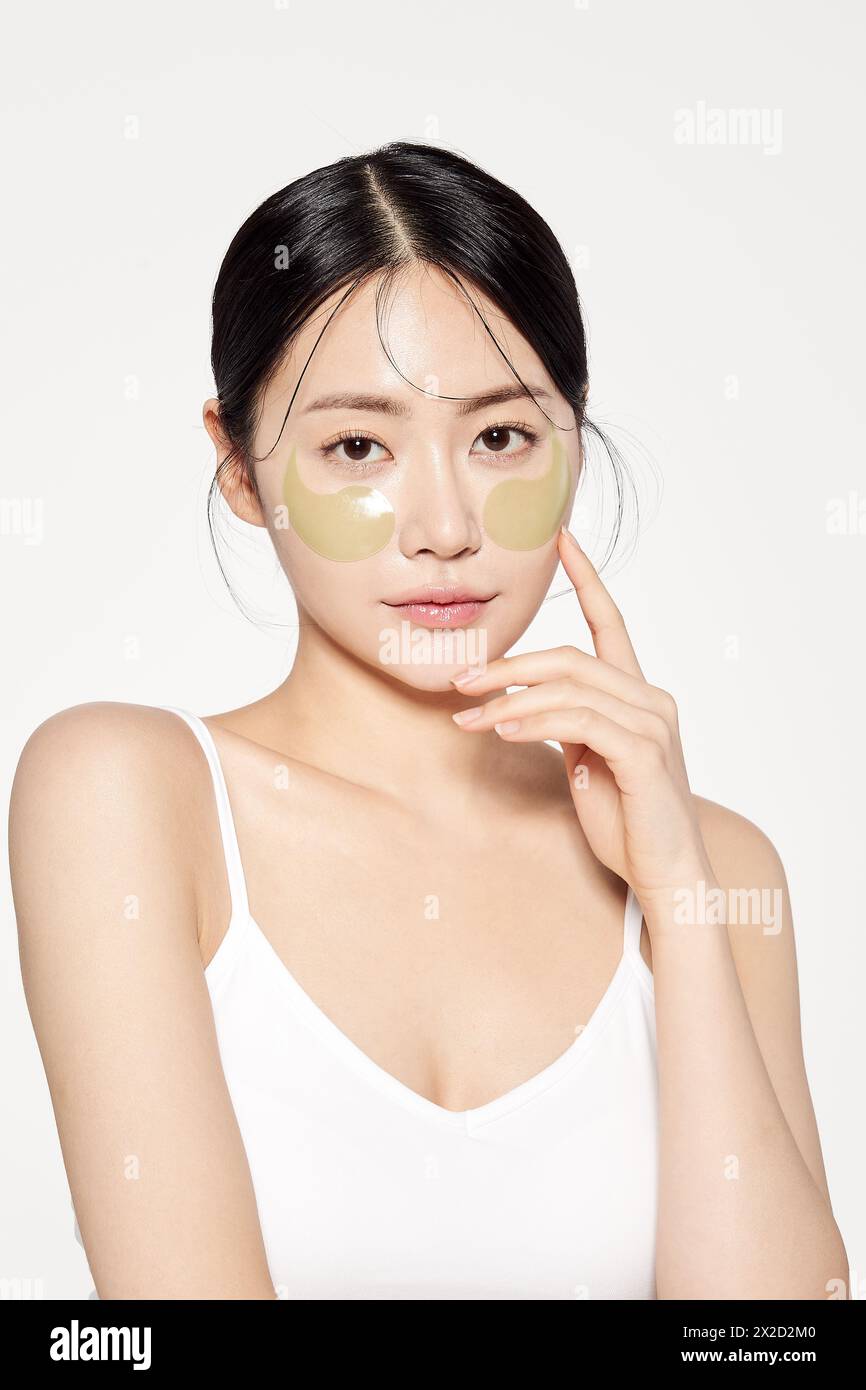 Femme asiatique posant avec des plaques oculaires sur les deux joues Banque D'Images