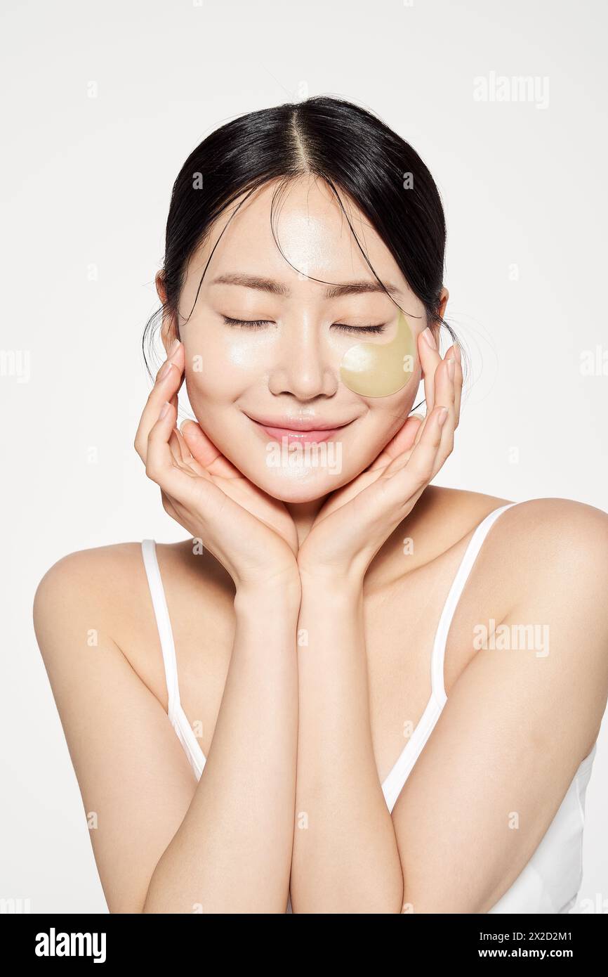 Femme asiatique avec des plaques oculaires sur son visage et ses yeux doucement fermés Banque D'Images