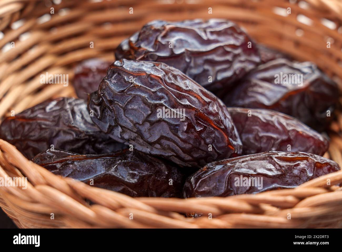 Dattes medjool séchées dans un bol en rotin en bois gros plan. Dessert arabe. Concept de nourriture traditionnelle Ramadan. Banque D'Images