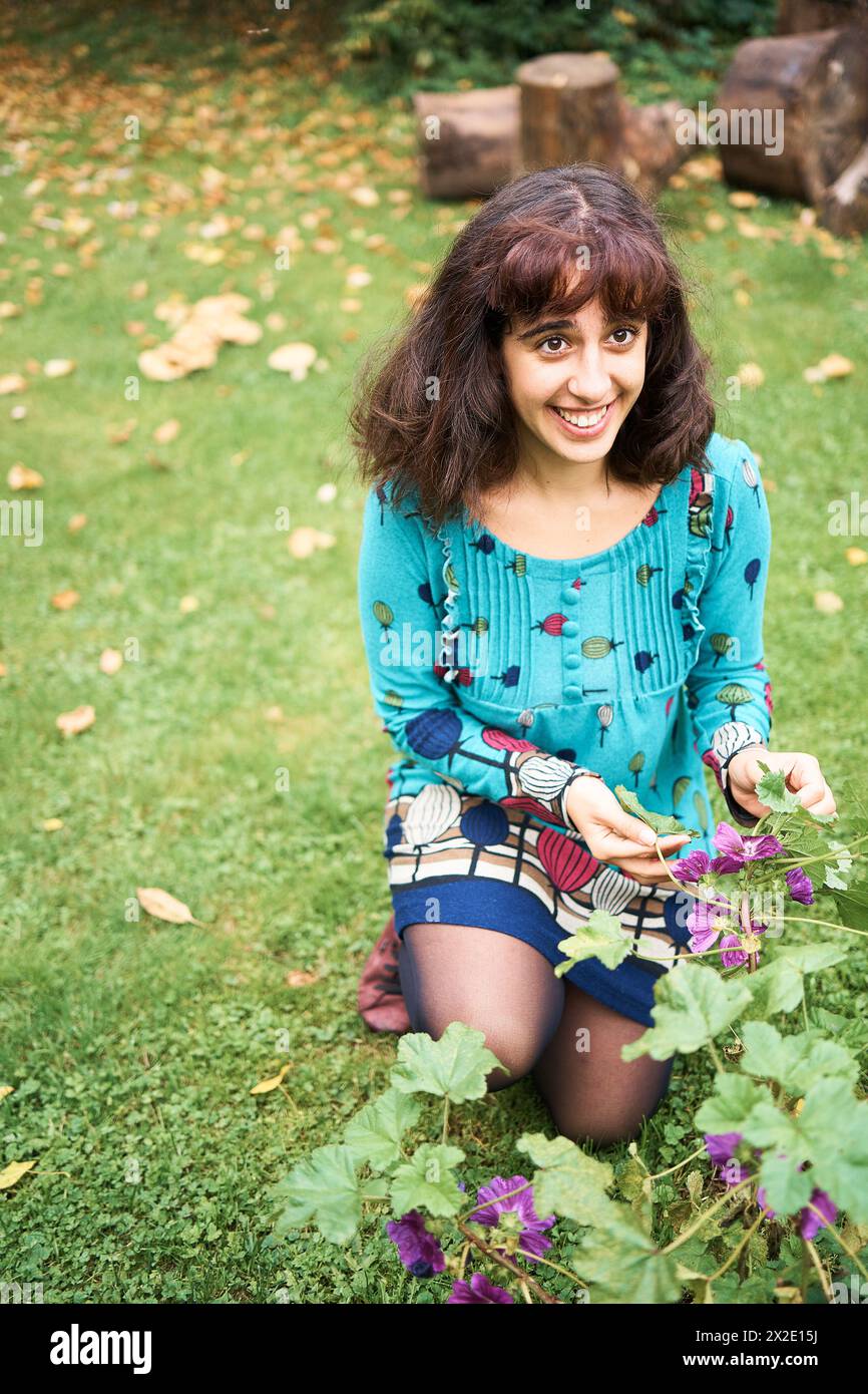 fille dans une robe avec des ballons regarde les fleurs dans le jardin Banque D'Images