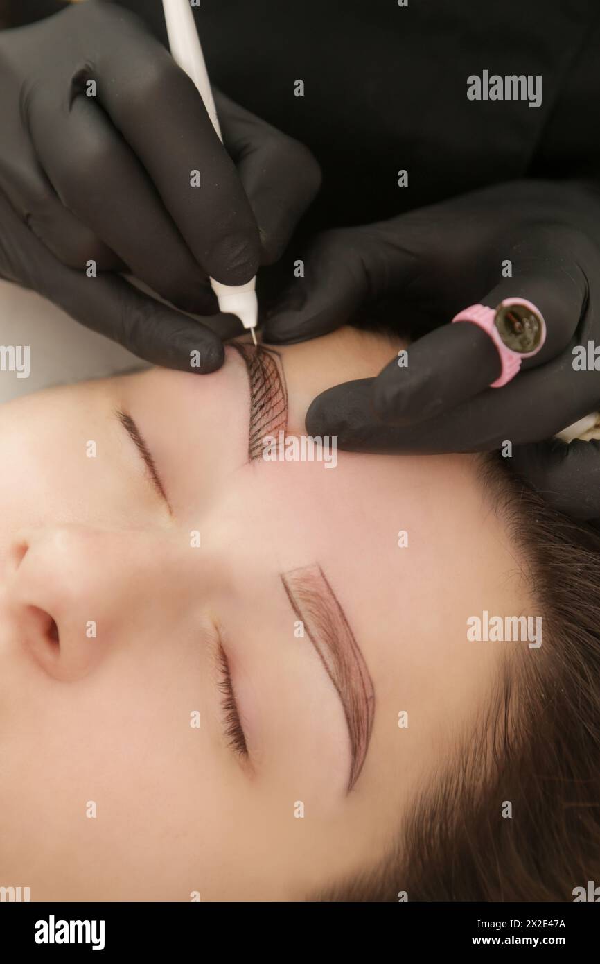 Microblading - technique de tatouage semi-permanent utilisée pour les sourcils en créant une illusion d'un sourcil plus défini et plus complet. Artiste fait Tiny h Banque D'Images