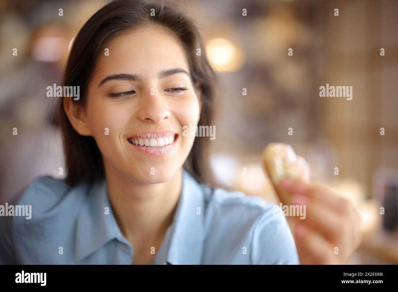 Femme heureuse avec un sourire blanc et des lèvres sales de sucre regardant croissant dans un restaurant Banque D'Images