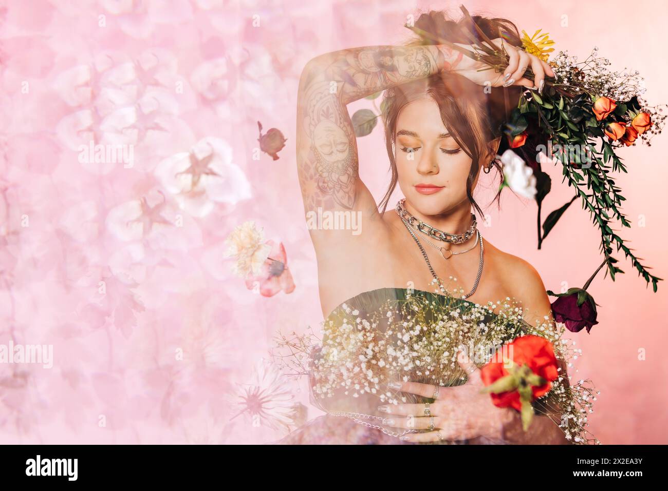 Portrait de studio aux tons roses d'une jeune femme entourée de fleurs Banque D'Images