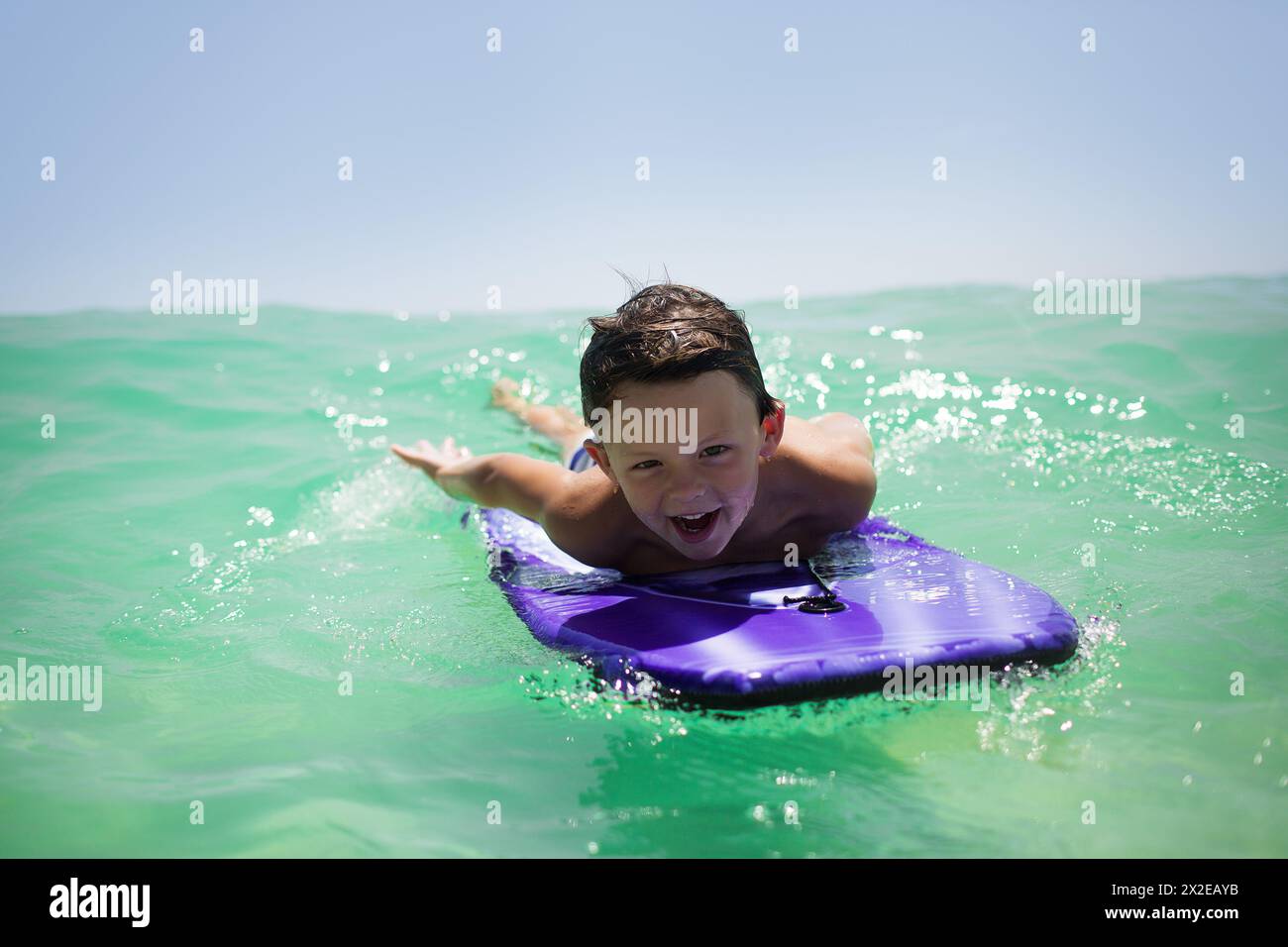 Boy Body Surfing joyeux sur une planche de boogie Banque D'Images