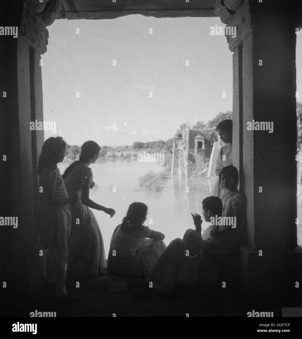 Des hommes et des femmes pendjabis sont silhouettés contre un cadre de fenêtre en pierre sur les rives d'une rivière en Inde pendant la campagne birmane entre 1941 et 1945. Banque D'Images