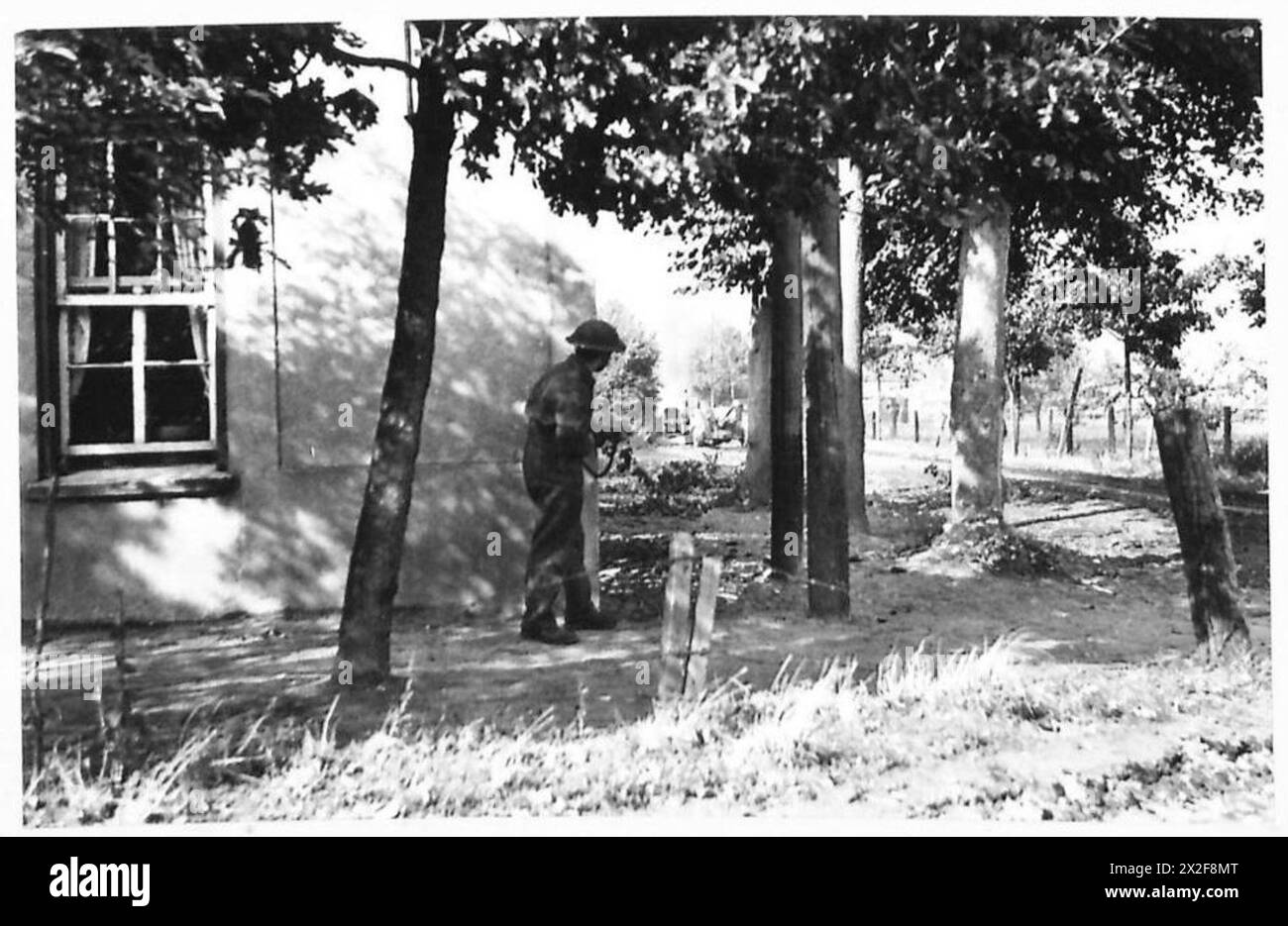 Lors de l'avance de la 11e division blindée vers Deurne, un conducteur observe un porte-avions touché par des tirs d'obus en éruption de flammes alors qu'il se met à couvert derrière un bâtiment. Banque D'Images