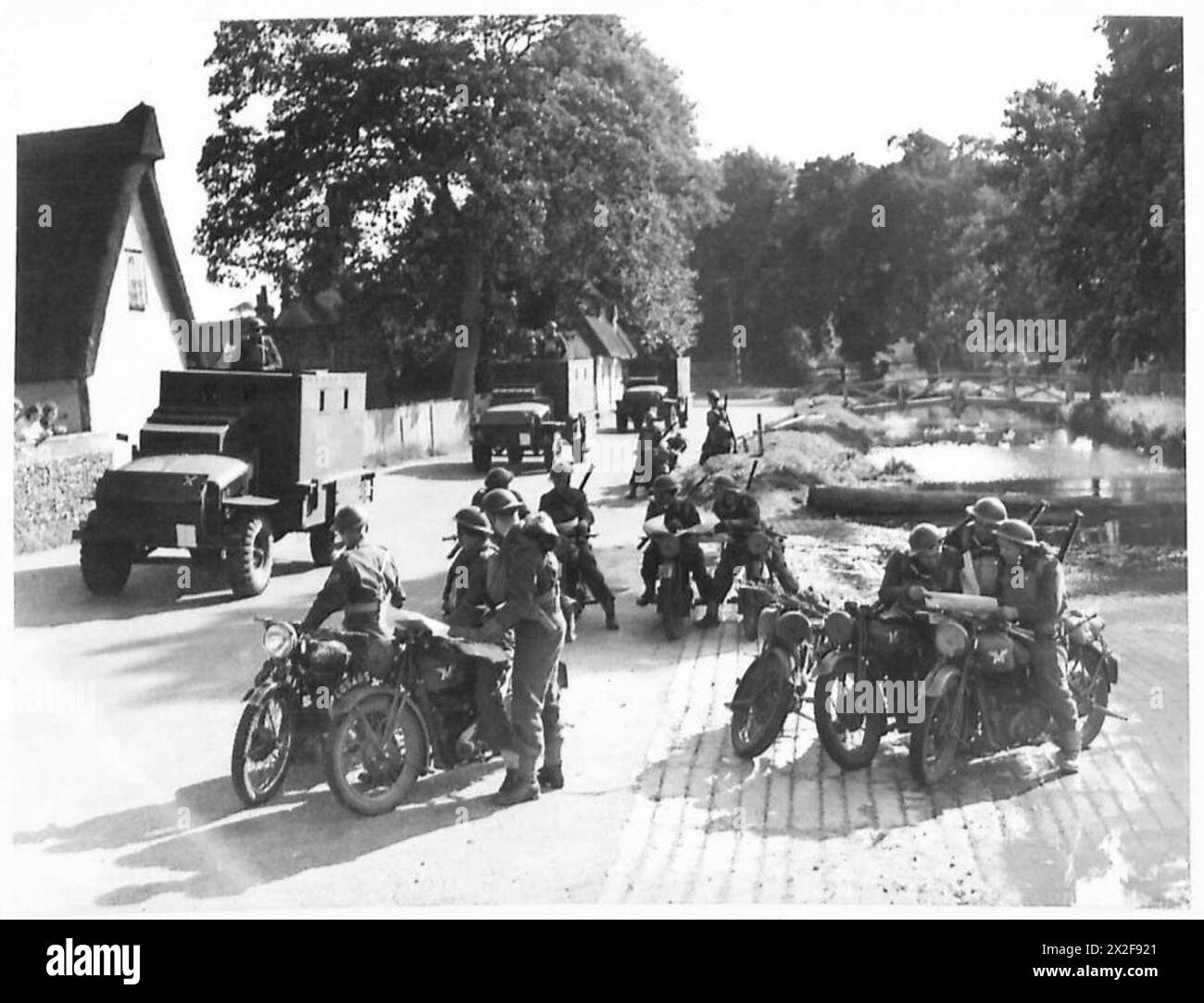 Une BRIGADE MOBILE DE RECONNAISSANCE - les motocyclistes de l'unité font une pause au bord de la route pour consulter leurs cartes et sont dépassés par les voitures blindées de l'unité British Army Banque D'Images