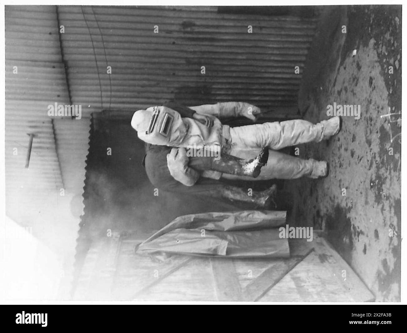 Un pompier adapté à l'amiante sauve une victime d'une cabane en feu à Buckland Tile Works près de Reigate pendant des opérations d'urgence en temps de guerre. Banque D'Images