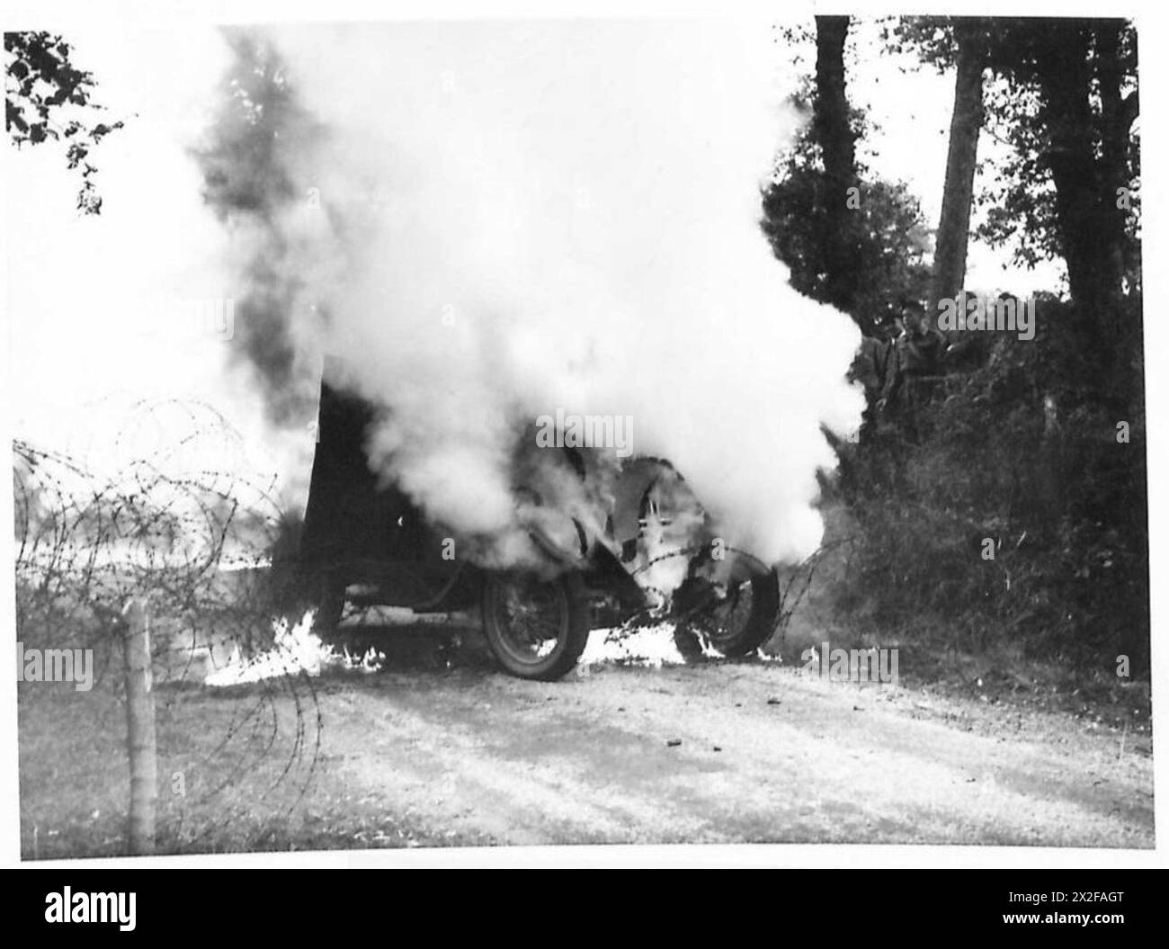 Une photographie de guerre montre un véhicule blindé enflammé après avoir été frappé par un cocktail Molotov, le véhicule étant arrêté contre une barrière routière. Cette image illustre l'utilisation de dispositifs incendiaires improvisés contre des cibles blindées pendant le combat. Banque D'Images