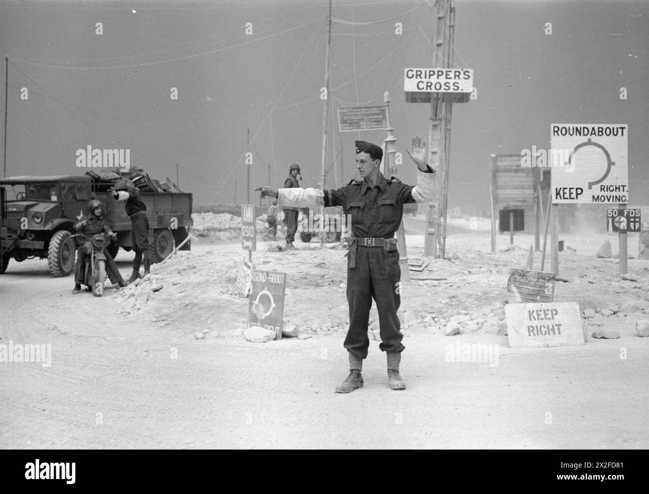 La police de la RAF contrôle la circulation au rond-point Gripper's Cross sur la route Caen–Bayeux en Normandie, avec les caporaux Brian Nash et Harry Petters dirigeant un motocycliste de l'armée. Banque D'Images