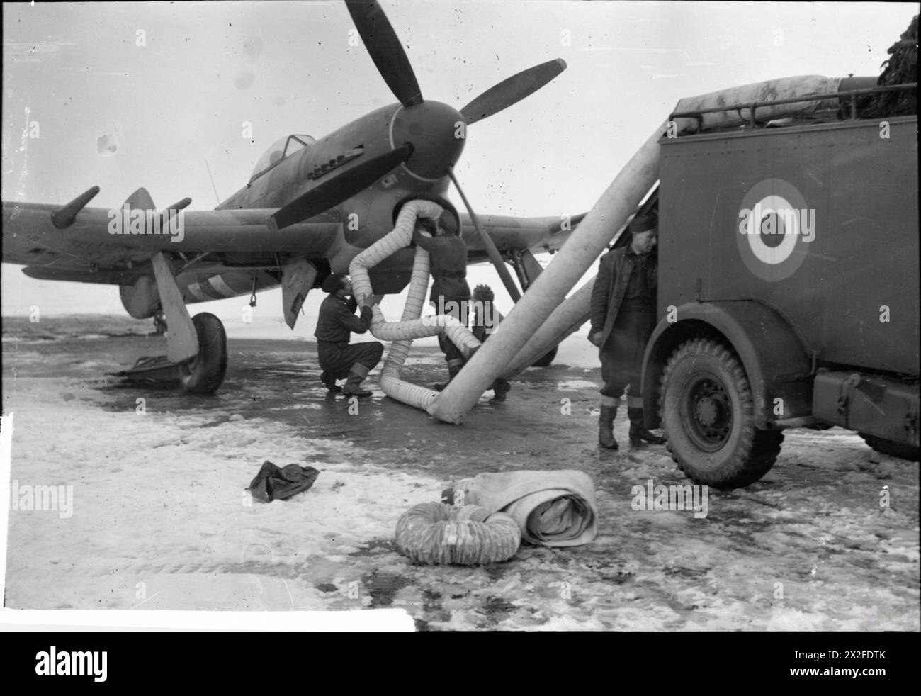 L'équipe au sol du n° 3208 entretenant Commando entretient un Hawker Typhoon Mark IB en insérant des tubes de préchauffage dans l'admission d'air et le radiateur pour maintenir le fonctionnement du moteur Napier Sabre dans des conditions enneigées à B58/Melsbroek, Belgique. Banque D'Images