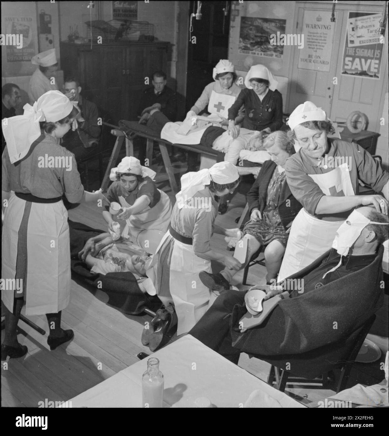 À Fulham, Londres, en 1942, des infirmières d'un poste de premiers soins ont soigné des travailleurs de la défense civile blessés pendant leur formation. Les patients comprenaient des blessures au visage, des blessures aux jambes et des blessures graves au dos examinées par une infirmière surintendante. Banque D'Images