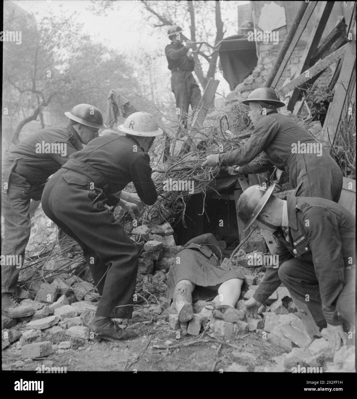 Les secouristes nettoient les décombres et les débris autour d'une femme coincée sous les briques, le bois et le fil de fer pendant la formation à la protection civile à Fulham, Londres, 1942. Les travailleurs portent des casques en acier marqués d'un « R » indiquant l'appartenance à l'équipe de secours. Banque D'Images