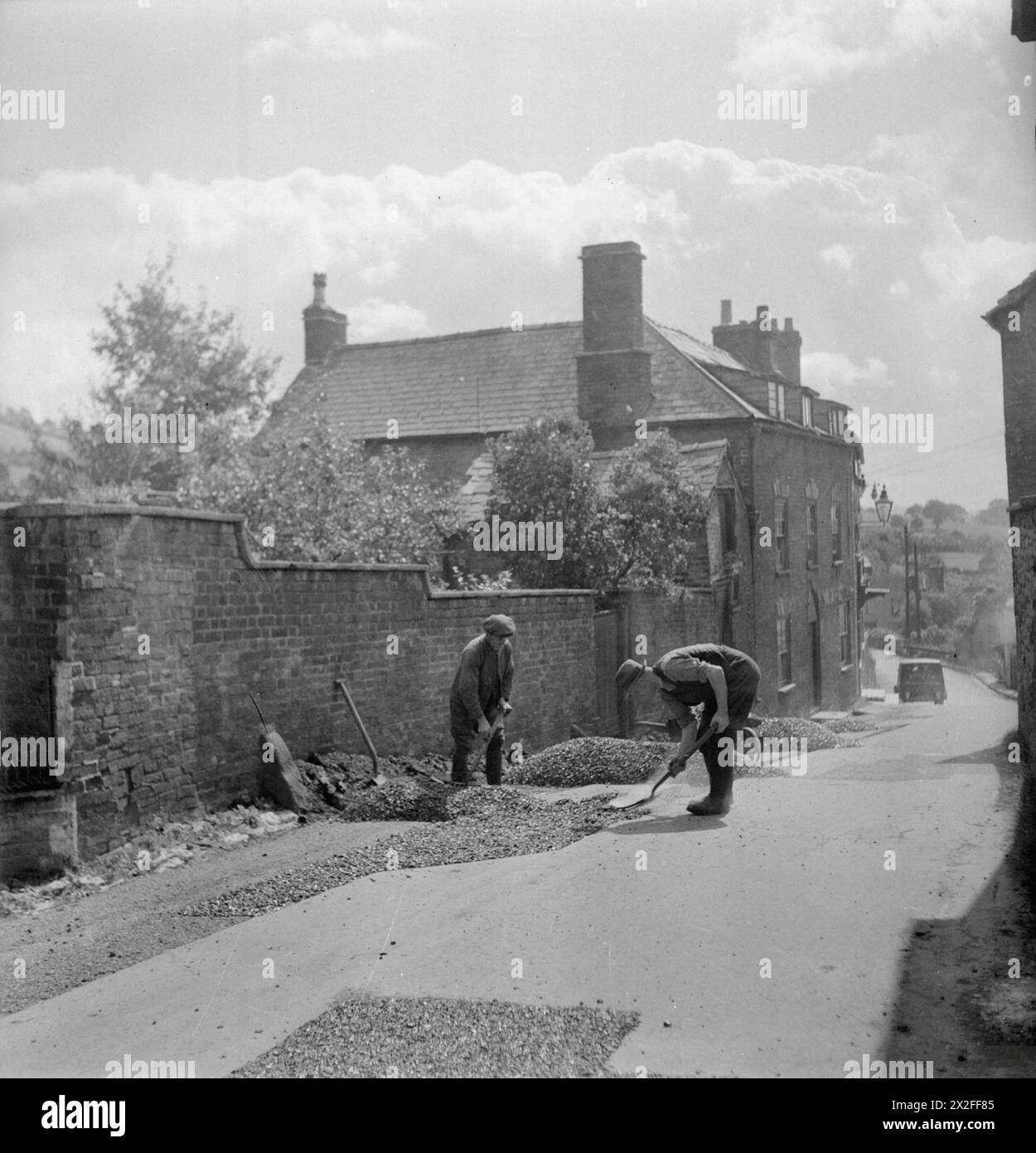 Des ouvriers resurfaçent et rectifient une route à Wotton-under-Edge, Gloucestershire en 1944 sous la supervision du conseil du comté de Gloucestershire. Les routes rurales sont entretenues par le Conseil du comté, les routes urbaines par le Conseil du district urbain. Banque D'Images