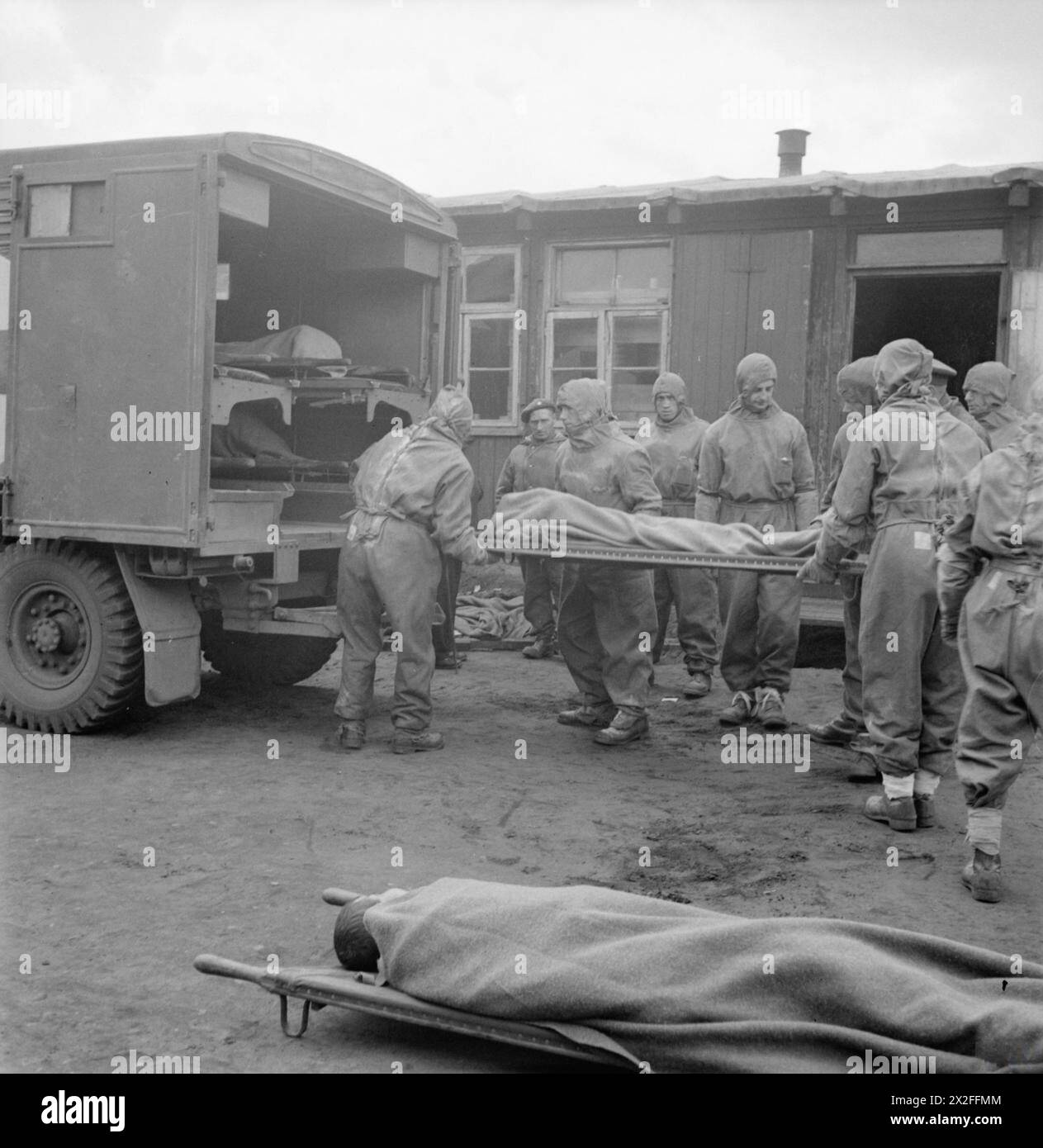 Des hommes du 11e Light Field Ambulance, Royal Army Medical corps, portant des vêtements de protection, évacuent un détenu atteint du typhus au camp n° 1 de Bergen-Belsen ; 6 500 malades avaient été évacués au 2 mai 1945. Banque D'Images
