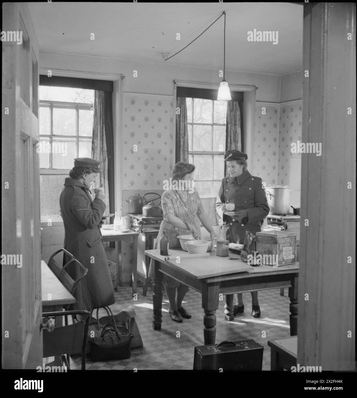 Dans un club YWCA à Norwich, Norfolk, 1944, des femmes, y compris une WAAF canadienne, prennent le thé et discutent avec le cuisinier avant de partir. Le club fournit des repas pour ceux qui doivent partir tôt. Banque D'Images