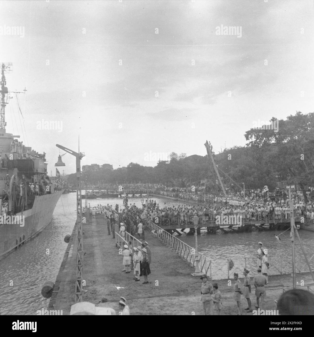 Des foules se rassemblent sur les quais de Saigon pour accueillir l'arrivée des forces d'occupation alliées lors de la réoccupation de l'Indochine française en 1945. Banque D'Images