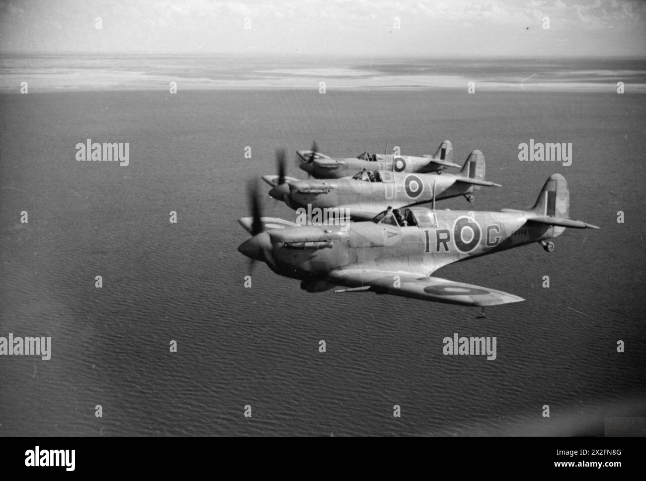 OPÉRATIONS DE LA ROYAL AIR FORCE AU MOYEN-ORIENT ET EN AFRIQUE DU NORD, 1939-1943. - Trois Spitfire LF Mark VBS de la 244e Escadre de la RAF basée à BU Grara, volant en formation tribord proche des échelons au large des côtes tunisiennes après avoir escorté des bombardiers légers sur une sortie vers Mareth. AB502 «IR-G», au premier plan, est l'avion personnel du Wing leader, Wing commander I R «Widge» Gleed, qu'il a piloté lorsqu'il a été abattu et tué au-dessus du Cap bon le 16 avril 1943, tandis que les deux avions qui l'accompagnaient sont ER220 «UF-V» et EP481 «UF-F» du No. 601 Squadron RAF. Tous les trois sont équipés de filtres à air Aboukir et ha Banque D'Images