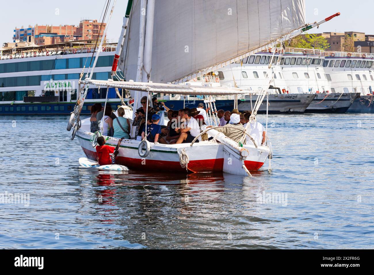 Garçon égyptien sur un paddleboard, mendiant des touristes sur un tour Felucca. Port d'Assouan, Nil, Égypte. Banque D'Images