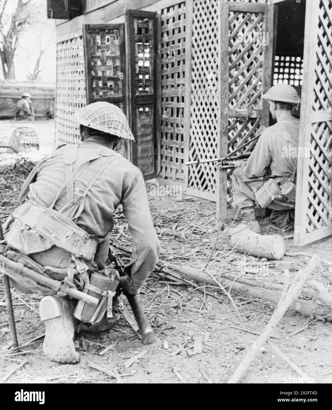 Les troupes de l'armée britannique avancent à travers des bâtiments à Ywathitgyi, en Birmanie, en février 1945, à la recherche de tireurs d'élite japonais pendant les opérations de la seconde Guerre mondiale. Banque D'Images