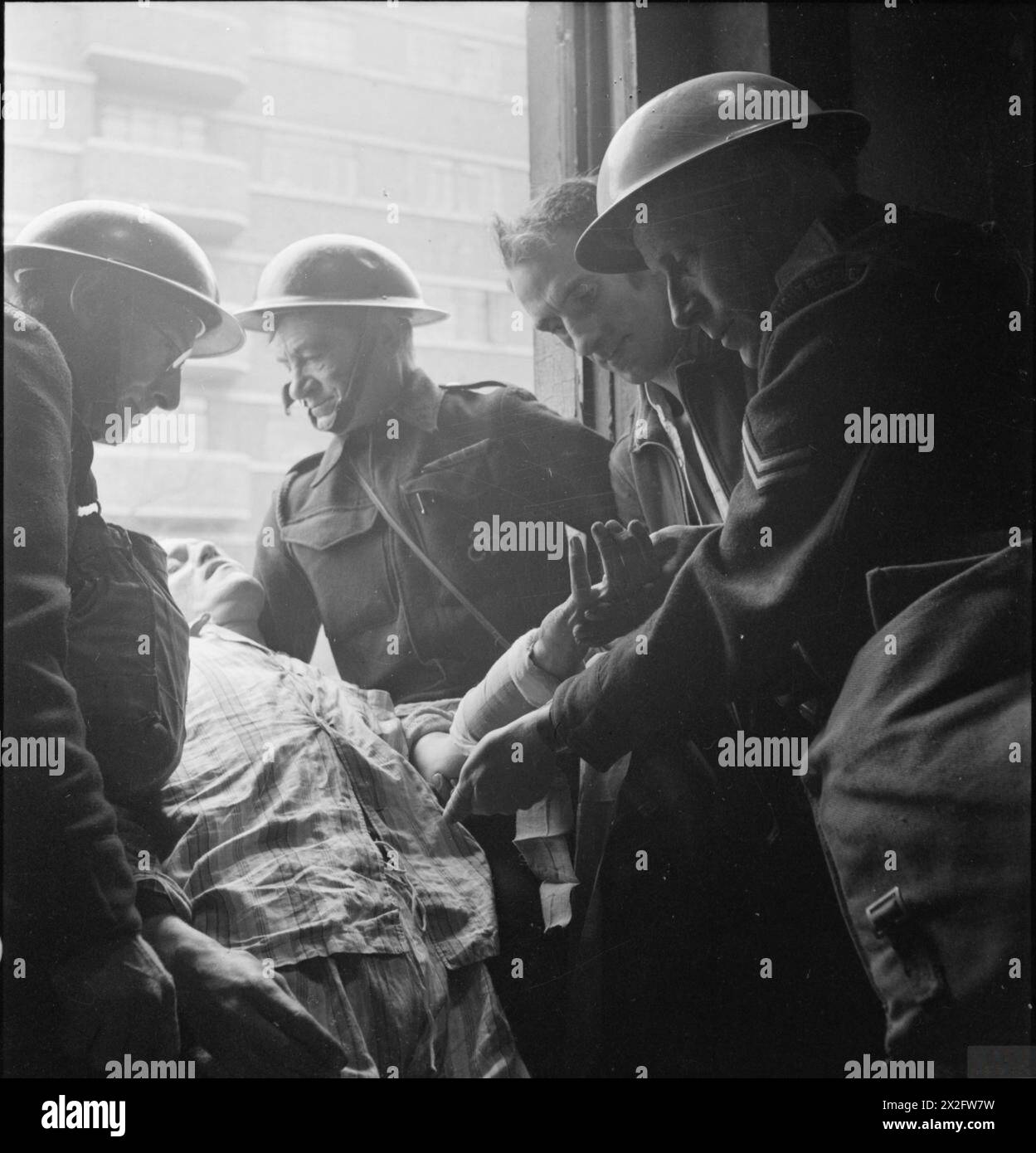 LA RECONSTRUCTION d'« UN INCIDENT » : FORMATION À LA DÉFENSE CIVILE À FULHAM, LONDRES, 1942 - le chef de l'équipe de « sauvetage léger » (à droite) et trois gardiens de la défense civile se préparent à abaisser une victime par une fenêtre à l'étage jusqu'à la rue. Cette photographie a été prise sur Edith Villas. Juste visible en arrière-plan à West Kensington court Banque D'Images
