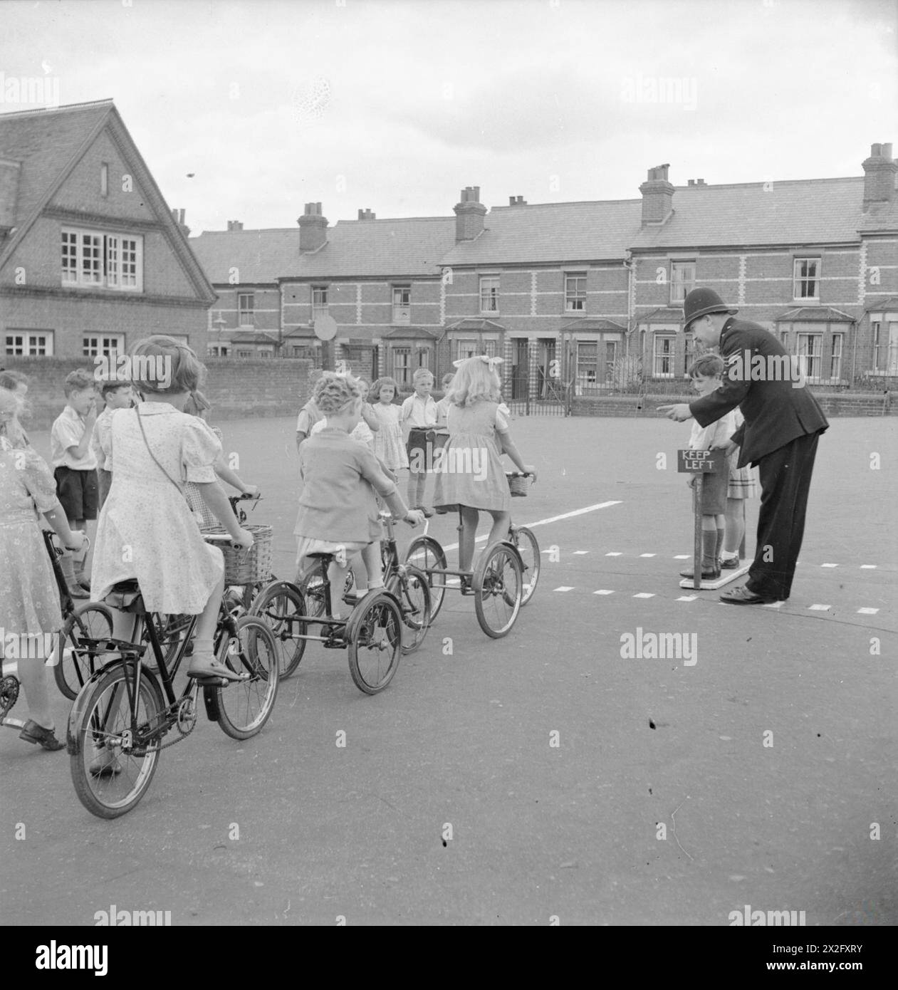 Un sergent de police enseigne la sécurité routière aux enfants à Battle Junior School Playground à Reading, Berkshire, 1945 ; les enfants pratiquent la traversée et la conduite de vélos et tricycles. Banque D'Images