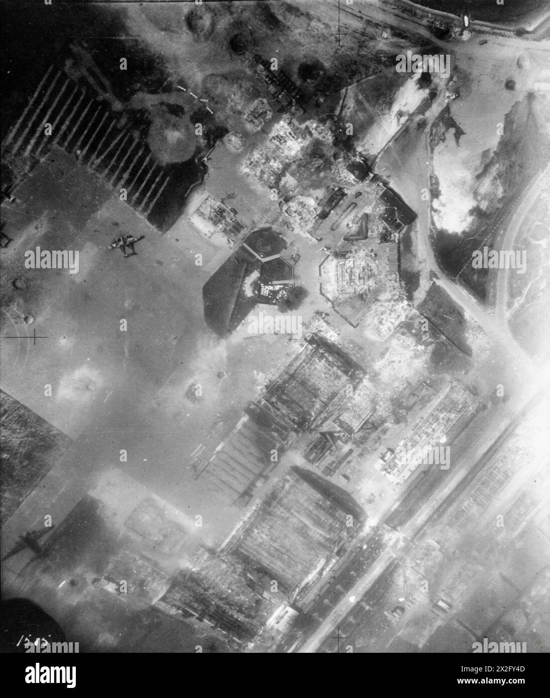 Le 10 mai 1940, Bristol Blenheim Mark IV du No. 15 Squadron RAF, No 2 Group, attaque des parachutistes et des avions allemands à Waalhaven aérodrome, Hollande. Des hangars et des bâtiments endommagés sont visibles, et un Fokker G.1 de la Royal Netherlands Air Force est sur le tablier en béton. Banque D'Images